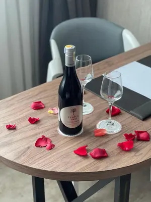 a bottle of wine and two glasses on a wooden table at Iconic Hotel in Bukit Mertajam