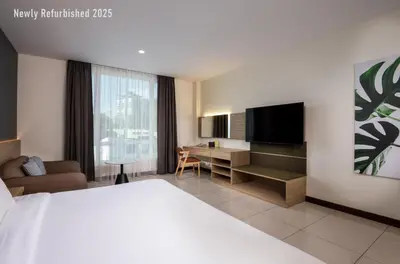 a hotel room with a bed and a desk with a television at One Pacific Hotel and Serviced Apartments in George Town