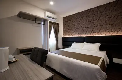 a hotel room with a large bed and a desk at Gurney Lodge in George Town