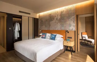 a bedroom with a large white bed and a chair at JEN Penang Georgetown by Shangri-La in George Town