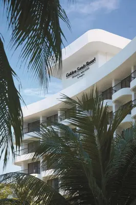 a white building with palm trees in front of it at Shangri-La Golden Sands, Penang in Batu Ferringhi