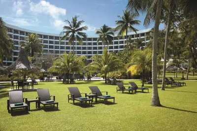 a park with chairs and palm trees and a building at Shangri-La Golden Sands, Penang in Batu Ferringhi