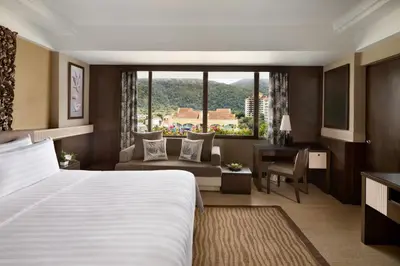 a hotel room with a large bed and a desk at Shangri-La Golden Sands, Penang in Batu Ferringhi