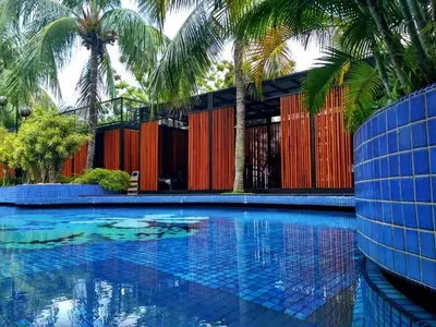 a swimming pool with palm trees and a building at Century Bay Private Residences in Bayan Lepas