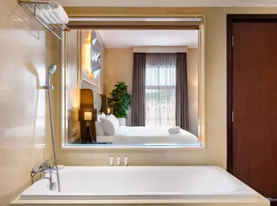 a bathroom with a large mirror over a bath tub at Eastin Hotel Penang in Bayan Lepas