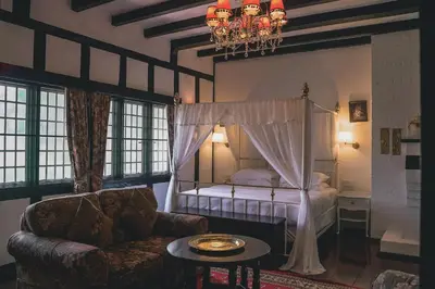 a bedroom with a bed and a couch and a table at The Smokehouse Hotel & Restaurant Cameron Highlands in Cameron Highlands