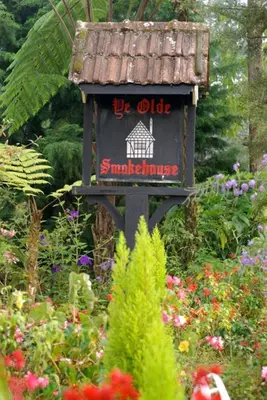 a sign in the middle of a garden with flowers at The Smokehouse Hotel & Restaurant Cameron Highlands in Cameron Highlands