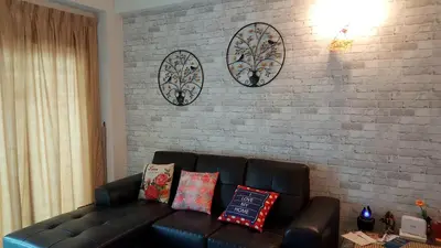 a living room with a couch and a brick wall at Sweet Homestay Penang in Bayan Lepas