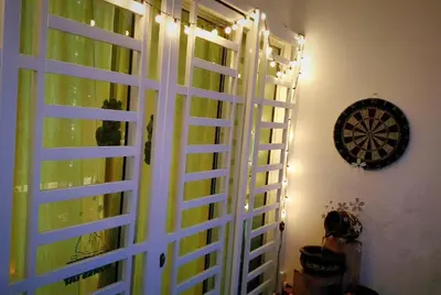 a window with green shutters and a dartboard on a wall at Sweet Homestay Penang in Bayan Lepas