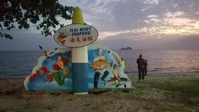 a sign on the beach next to the water at Sweet Homestay Penang in Bayan Lepas