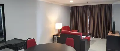 a room with red chairs and a table and a television at Leisure Cove Hotel and Apartments in George Town
