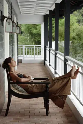 a woman laying in a hammock on a porch at Cameron Highlands Resort - Small Luxury Hotels of the World in Cameron Highlands