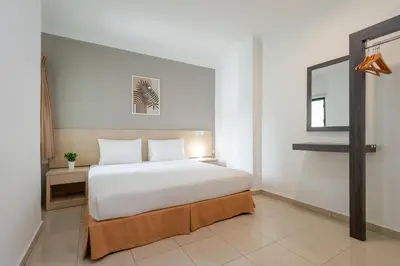 a bedroom with a large white bed and a mirror at Golden View Serviced Apartments in George Town