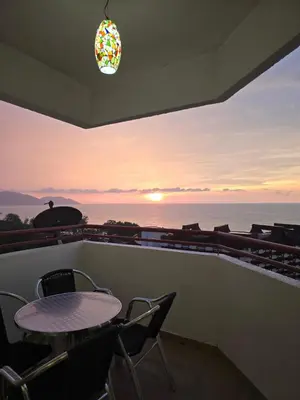 a table and chairs on a balcony with a view of the ocean at Green Ocean Seaview Apartment in Batu Ferringhi