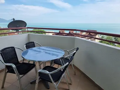 a table and chairs on a balcony with the ocean at Green Ocean Seaview Apartment in Batu Ferringhi