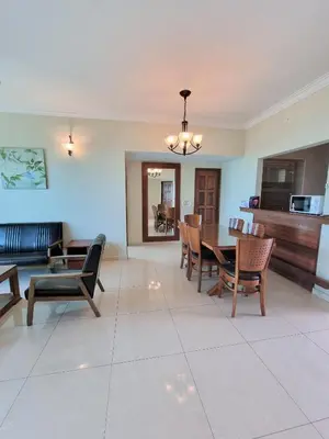 a dining room and living room with a table and chairs at Green Ocean Seaview Apartment in Batu Ferringhi