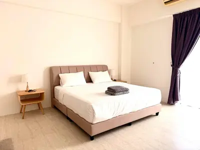 a bedroom with a bed and a table and a window at By The Sea Suites - Managed by SDBMS in Batu Ferringhi