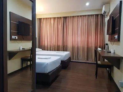 a hotel room with two beds and a desk at Garden Inn, Penang in George Town