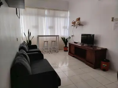 a living room with two black couches and a television at Penang Tg Bungah Permai Ria Apartment in Tanjung Bungah