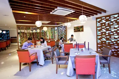 a group of people sitting at tables in a restaurant at Vouk Hotel Suites, Penang in George Town