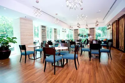 a restaurant with blue chairs and tables and windows at Vouk Hotel Suites, Penang in George Town