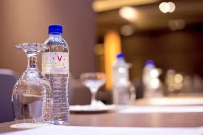 a bottle of water sitting on a table with a glass at Vouk Hotel Suites, Penang in George Town