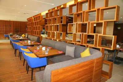 a restaurant with wooden tables and blue chairs at Novotel Taiping in Taiping