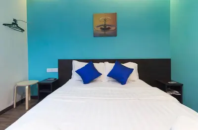 a bedroom with a white bed with blue walls at Clover Hotel Ipoh in Ipoh