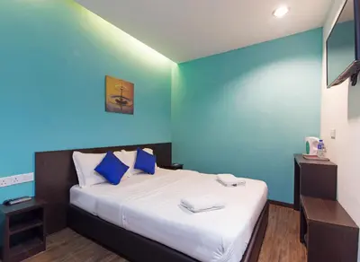 a bedroom with a bed with a blue wall at Clover Hotel Ipoh in Ipoh