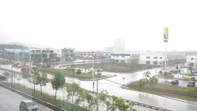 a city street in the rain with cars on the road at Clover Hotel Ipoh in Ipoh