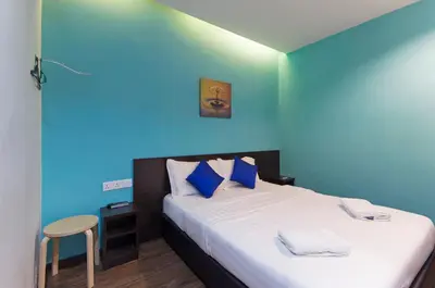 a bedroom with a bed with a blue wall at Clover Hotel Ipoh in Ipoh