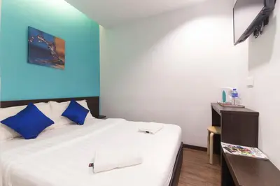 a bedroom with a large white bed with blue walls at Clover Hotel Ipoh in Ipoh