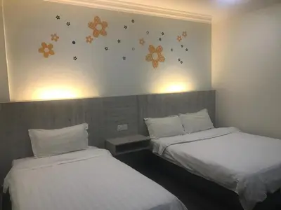 two beds in a room with flowers on the wall at Tambun Inn Hotel in Ipoh