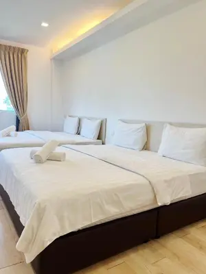 two beds in a room with white sheets and pillows at Vvip Hotel in Hutan Melintang