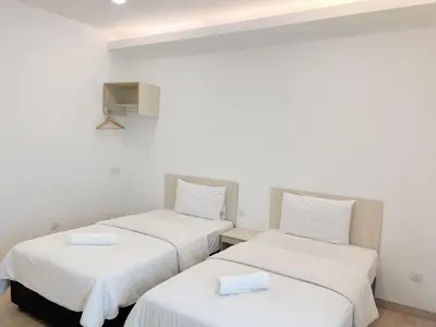 two twin beds in a room with white walls at Vvip Hotel in Hutan Melintang