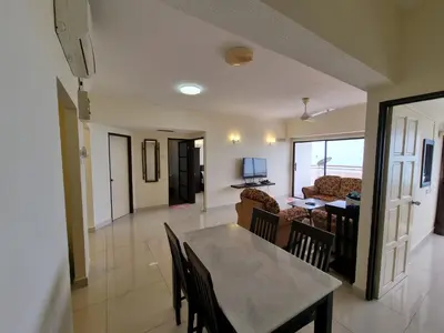 a dining room and living room with a table and chairs at Aloka Seaview Apartment in Batu Ferringhi