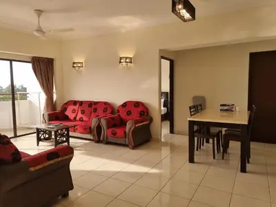 a living room with red couches and a table at Aloka Seaview Apartment in Batu Ferringhi