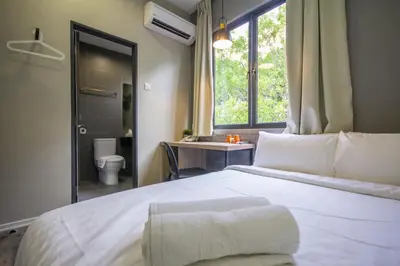 a bedroom with a white bed and a bathroom at Chariton Hotel Alma in Bukit Mertajam