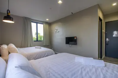 a hotel room with two beds and a tv at Chariton Hotel Alma in Bukit Mertajam
