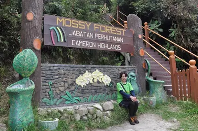 a woman is sitting in front of a sign at Orchid Haven in Cameron Highlands