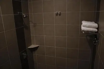 a bathroom with a shower stall with towels on it at Austin GuestHouse in Ipoh