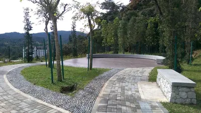 a walkway with a bench and a park with trees at Strawberry Homestay in Cameron Highlands
