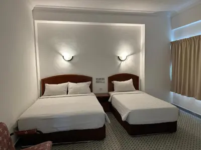 a hotel room with two beds and a window at New Caspian Hotel in Ipoh