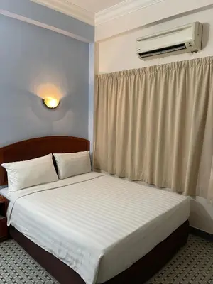 a bedroom with a bed and a window with a air conditioner at New Caspian Hotel in Ipoh