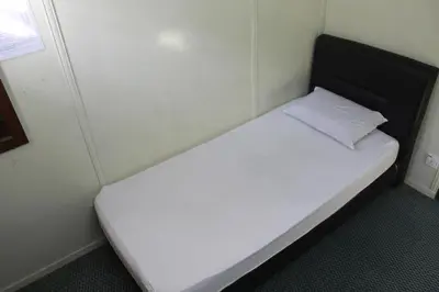 a small white bed in a small room at Old Penang Hotel - Trang Road in George Town