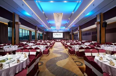 a banquet hall with white tables and red chairs at Purest Hotel Sungai Petani in Sungai Petani