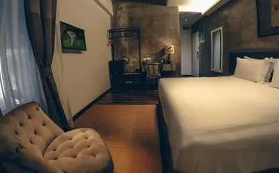 a bedroom with a bed and a chair in it at Merton Hotel Ipoh in Ipoh