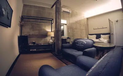 a living room with a couch and a table and a bed at Merton Hotel Ipoh in Ipoh