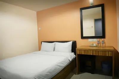 a small bedroom with a bed and a mirror at Brezza Hotel Lumut in Lumut