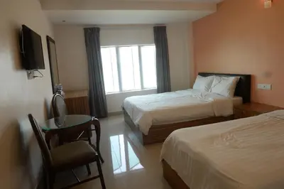 a hotel room with two beds and a table and a window at Brezza Hotel Lumut in Lumut